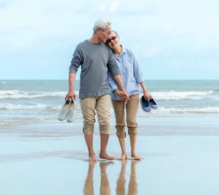 An older couple walking comfortably along a beach, staying active together