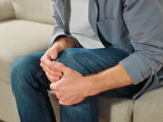 A person holding a sore knee, a common weight-bearing joint affected by extra load